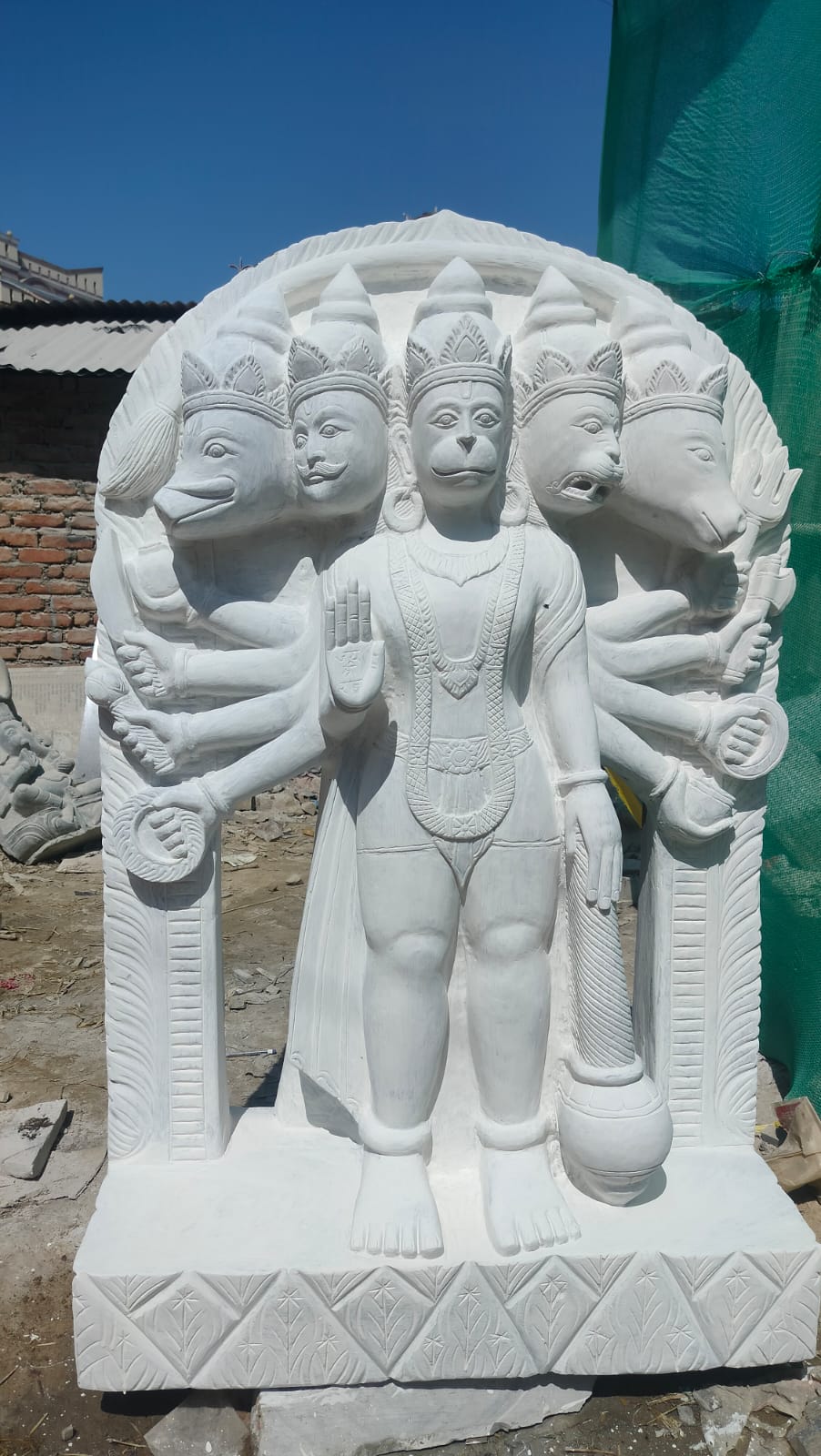 This magnificent Panchamukhi Hanuman Murti is handcrafted by experienced Nepali artisans using high-quality natural marble and traditional carving techniques. The five faces of Lord Hanuman symbolize different divine energies: Hanuman – Strength, devotion, and courage Narasimha – Protection from evil and fear Garuda – Freedom from negativity and harmful influences Varaha – Prosperity, stability, and protection of the Earth Hayagriva – Knowledge, wisdom, and intelligence Intricately carved with exceptional attention to detail, this sacred sculpture reflects Nepal's rich artistic heritage. It is a powerful symbol of faith, protection, and spiritual strength, making it an ideal centerpiece for temples, homes, and meditation spaces. Features Handmade by skilled Nepali artisans Crafted from premium-quality natural marble Traditional Nepali stone carving with intricate detailing Depicts the sacred five-faced form of Lord Hanuman Symbolizes protection, courage, wisdom, prosperity, and devotion Ideal for temples, home shrines, meditation rooms, and spiritual centers Weather-resistant and suitable for both indoor and outdoor installation Specifications Material: Natural Marble Origin: Nepal Finish: Hand-Carved White Marble Style: Traditional Nepali Religious Sculpture Usage: Worship, Temple Decoration, Home Decoration, Meditation Space, Garden Décor, Gift Item Bring the divine blessings of Panchamukhi Hanuman into your home or temple with this beautifully handcrafted marble murti. A timeless symbol of strength, protection, wisdom, and unwavering devotion, it showcases the exceptional craftsmanship of Nepalese artisans and serves as a sacred addition to any spiritual space.